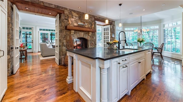 kitchen featuring pendant lighting, sink, a kitchen island with sink, plenty of natural light, and white cabinets