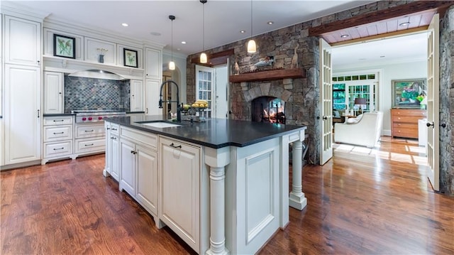 kitchen featuring white cabinetry, decorative light fixtures, sink, and a center island with sink