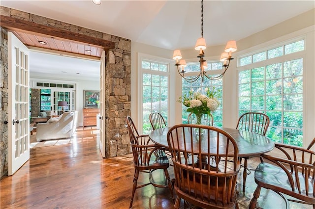 dining area featuring a notable chandelier, hardwood / wood-style flooring, a wealth of natural light, and french doors