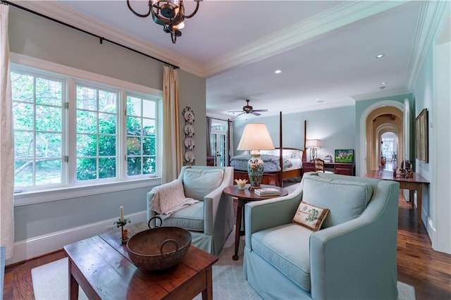 sitting room with hardwood / wood-style floors, crown molding, and ceiling fan with notable chandelier