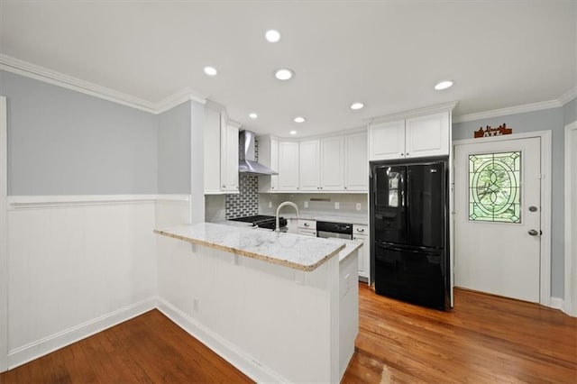 2100 Shady Ln, Tucker, GA 30084 - kitchen featuring freestanding refrigerator, wall chimney range hood, a peninsula, ornamental molding, and white cabinets