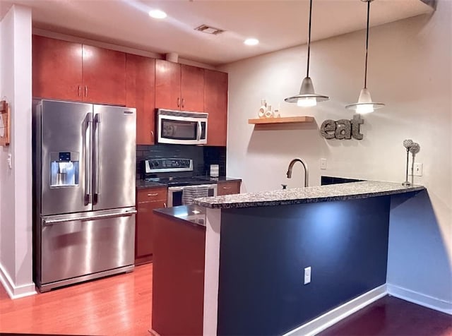400 W Peachtree St NW Unit 3216, Atlanta, GA 30308 - kitchen featuring stainless steel appliances, a peninsula, backsplash, dark countertops, and wood finished floors