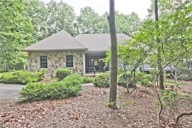 single story home featuring stone siding and roof with shingles