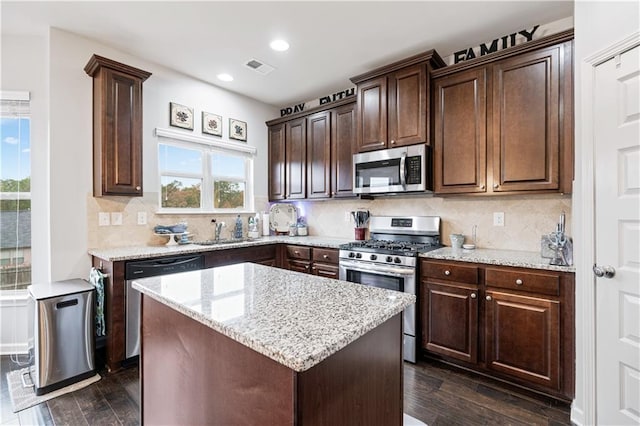 kitchen featuring appliances with stainless steel finishes, dark wood-type flooring, a kitchen island, and plenty of natural light