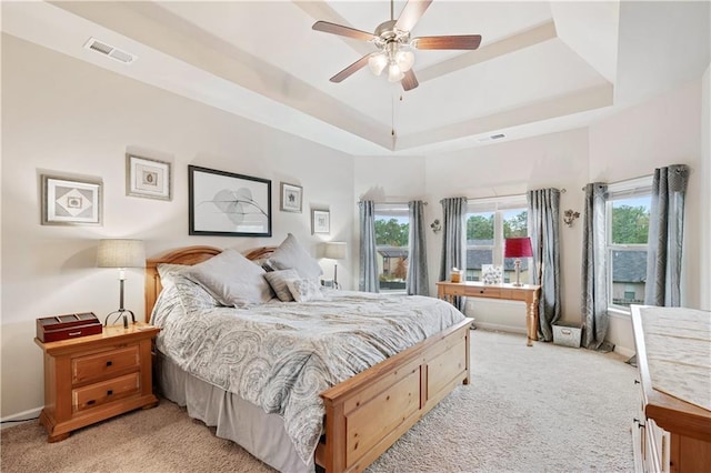 carpeted bedroom featuring ceiling fan and a raised ceiling