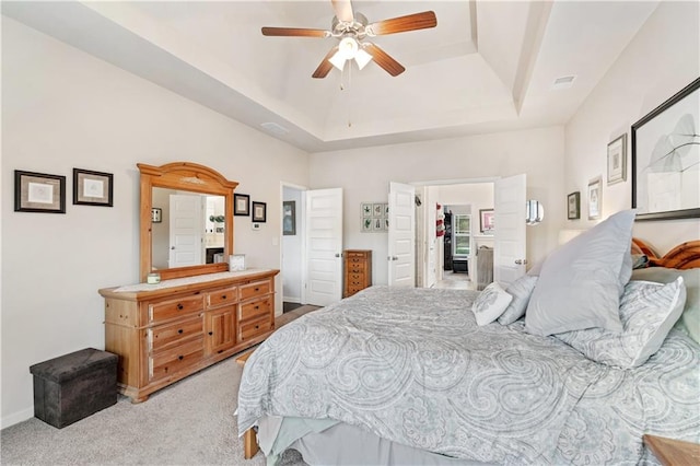 bedroom featuring ceiling fan, light carpet, and a tray ceiling