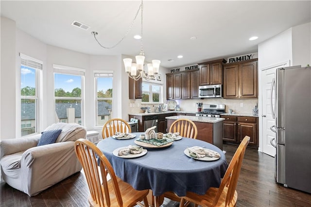 dining area with dark hardwood / wood-style flooring, a healthy amount of sunlight, sink, and an inviting chandelier