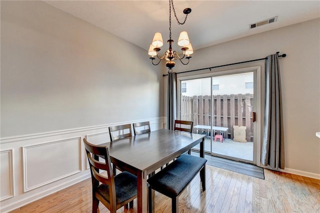 dining area with light wood-type flooring and an inviting chandelier