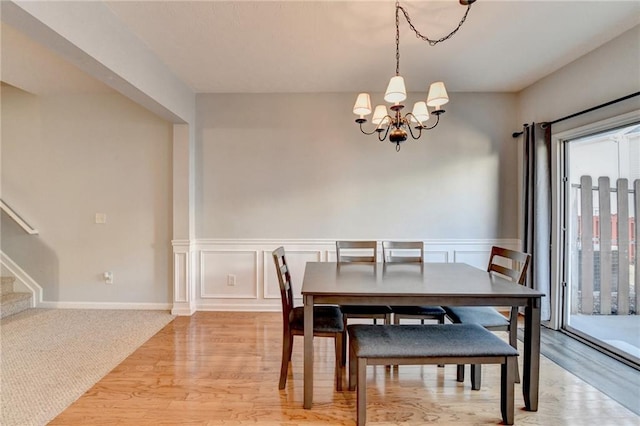 dining area with light hardwood / wood-style floors and an inviting chandelier