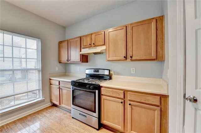 kitchen featuring light brown cabinetry, light hardwood / wood-style floors, and stainless steel gas range oven