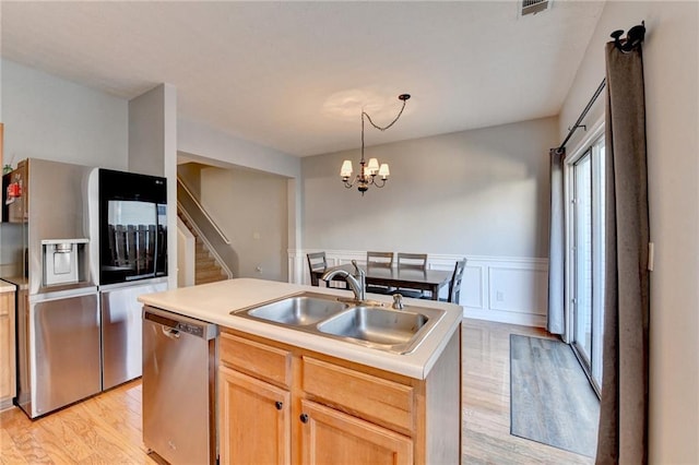 kitchen featuring a chandelier, stainless steel appliances, an island with sink, light brown cabinetry, and sink