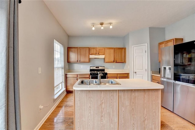 kitchen featuring stainless steel range oven, sink, light hardwood / wood-style floors, a kitchen island with sink, and light brown cabinets