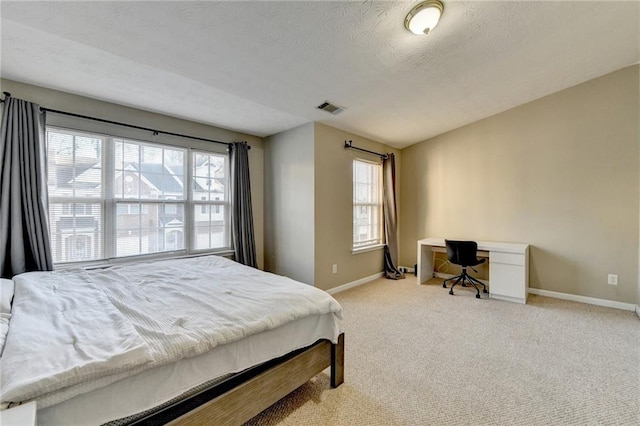 bedroom featuring a textured ceiling and light carpet