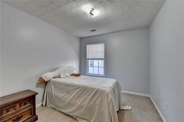 bedroom with a textured ceiling and light carpet