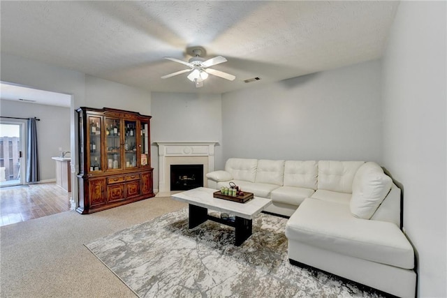 living room with a textured ceiling, ceiling fan, and light carpet