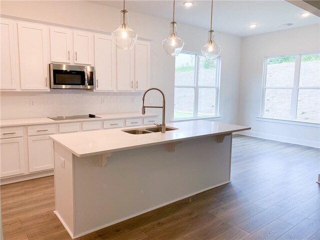 kitchen with white cabinets, a kitchen island with sink, sink, and plenty of natural light