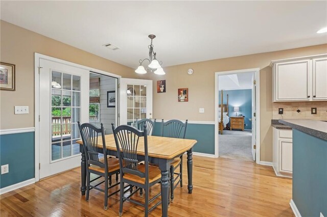 dining room with a chandelier, light wood finished floors, and baseboards