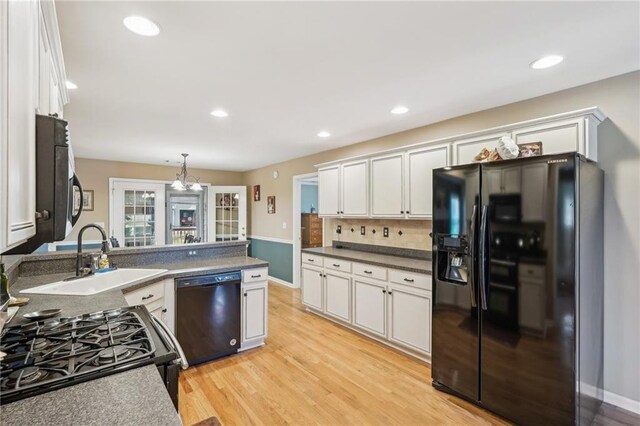 kitchen with black appliances, a sink, white cabinetry, light wood-style flooring, and recessed lighting