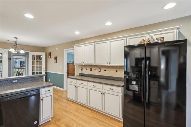 kitchen featuring black appliances, dark countertops, tasteful backsplash, pendant lighting, and light wood finished floors
