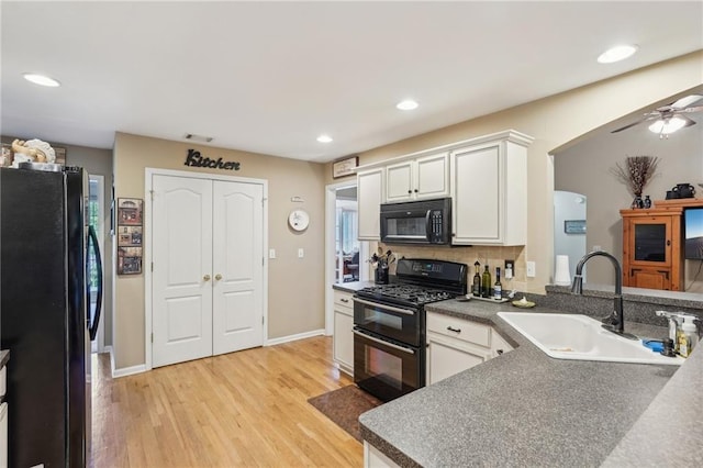 kitchen featuring black appliances, a sink, light wood-style floors, recessed lighting, and white cabinets