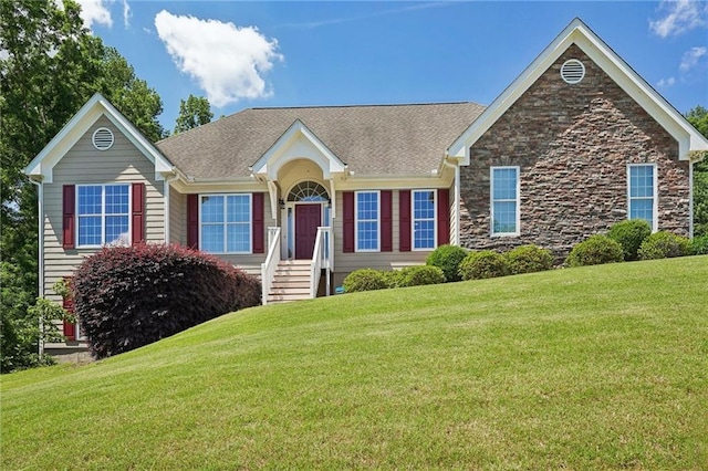 ranch-style home featuring a front lawn, stone siding, and a shingled roof