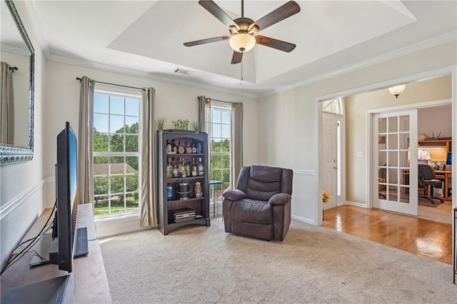 sitting room with carpet, a raised ceiling, ceiling fan, ornamental molding, and french doors