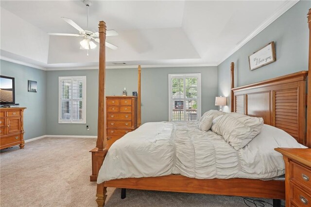 bedroom with carpet, crown molding, ceiling fan, a tray ceiling, and baseboards