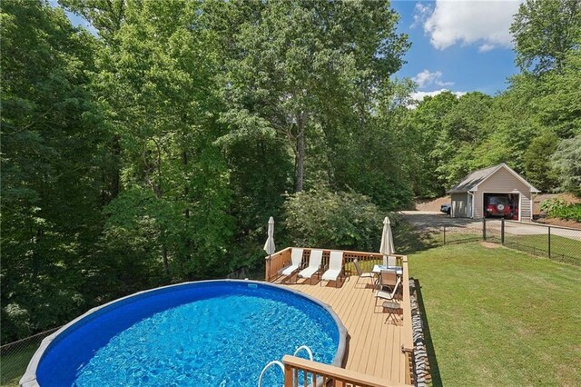 outdoor pool with a wooden deck, an outdoor structure, and a wooded view