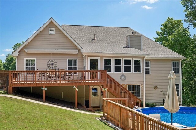 rear view of house with a wooden deck, a lawn, stairs, and an outdoor pool