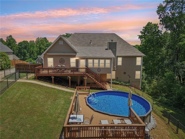 back of house at dusk featuring a deck, stairs, and a shingled roof