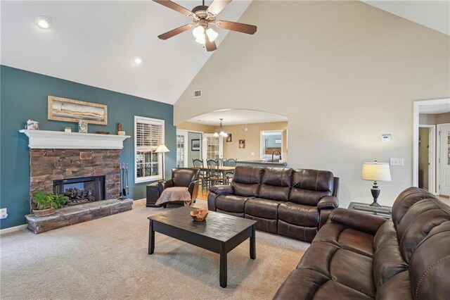 carpeted living area featuring high vaulted ceiling, arched walkways, a ceiling fan, a stone fireplace, and recessed lighting