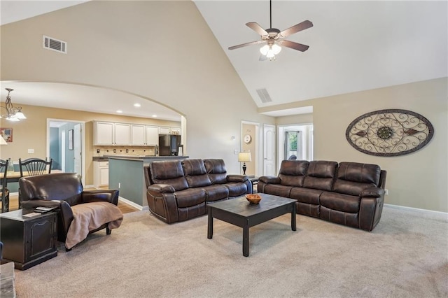 living area featuring high vaulted ceiling, light carpet, ceiling fan, arched walkways, and a chandelier