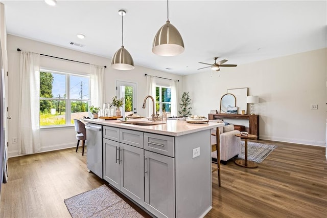 kitchen with gray cabinets, a sink, stainless steel dishwasher, dark wood-type flooring, and light countertops