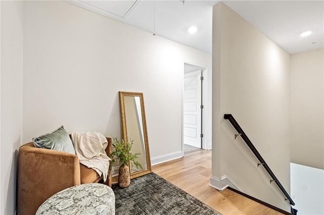 sitting room featuring an upstairs landing, light wood-type flooring, baseboards, recessed lighting, and attic access