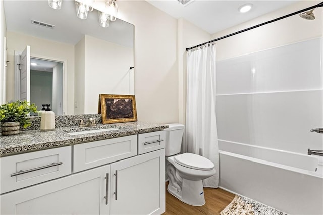 bathroom with wood finished floors, toilet, vanity, and shower / bath combination with curtain