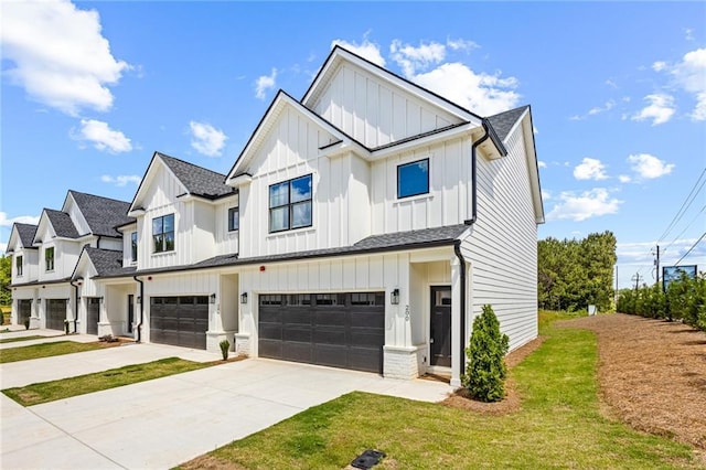 modern inspired farmhouse with board and batten siding, an attached garage, driveway, a front lawn, and roof with shingles