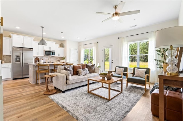 living room with a ceiling fan, light wood-type flooring, and recessed lighting