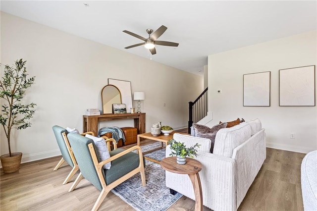 living room featuring wood finished floors, a ceiling fan, stairway, and baseboards