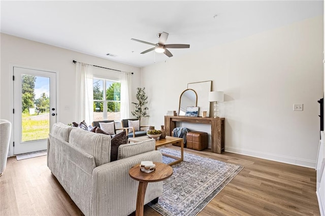 living room with wood finished floors, a ceiling fan, and baseboards