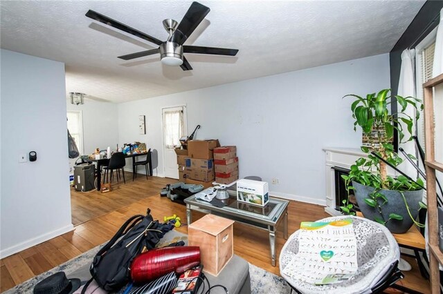 57 George Byrom Rd, Newnan, GA 30263 - living room with baseboards, ceiling fan, a fireplace, a textured ceiling, and wood finished floors