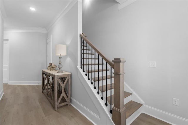 staircase with ornamental molding and hardwood / wood-style floors