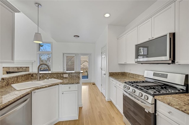 kitchen featuring stone countertops, pendant lighting, white cabinetry, sink, and stainless steel appliances