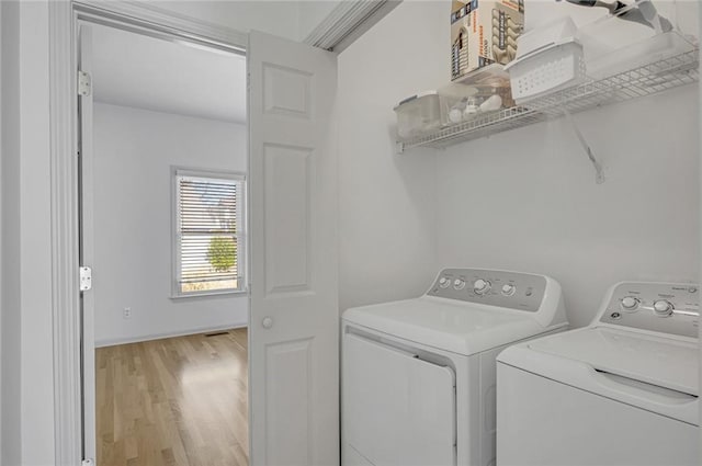 clothes washing area featuring washer and clothes dryer and light hardwood / wood-style flooring