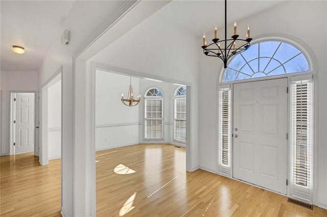 foyer featuring light wood-type flooring and a chandelier