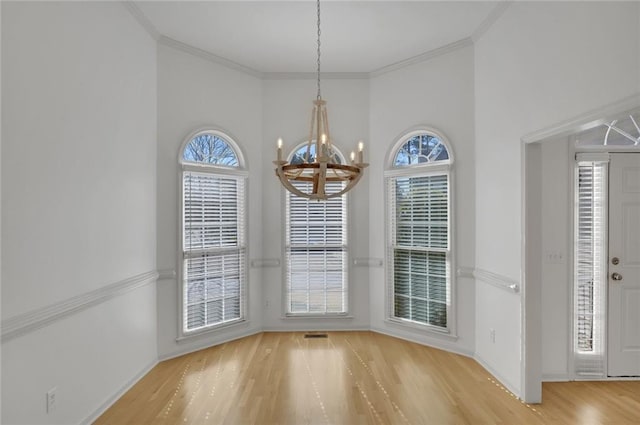 unfurnished dining area featuring an inviting chandelier, ornamental molding, and wood-type flooring