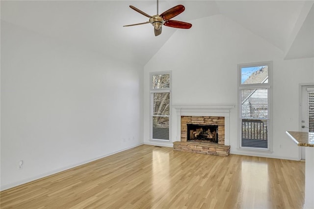 unfurnished living room featuring high vaulted ceiling, a fireplace, light hardwood / wood-style floors, and ceiling fan