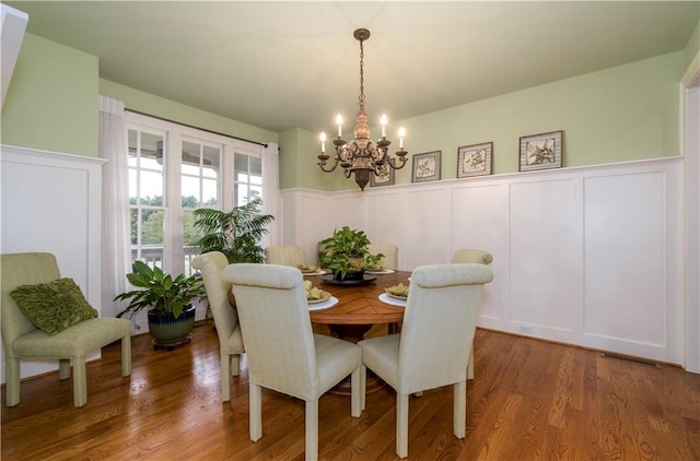 dining space with hardwood / wood-style flooring and a chandelier