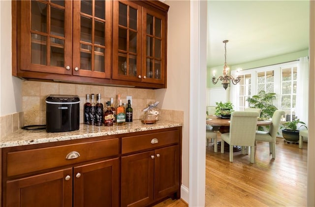 bar with tasteful backsplash, light stone countertops, and light hardwood / wood-style floors