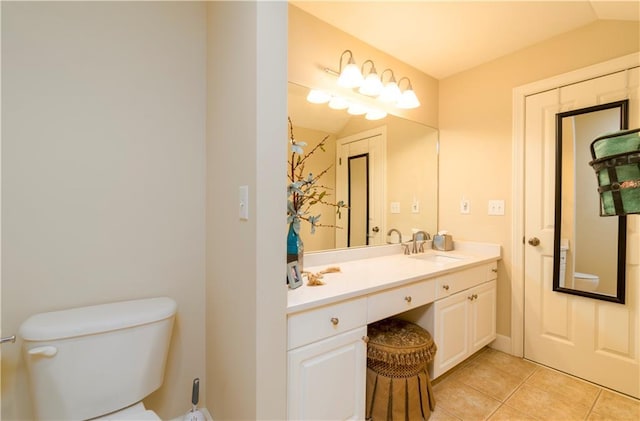 bathroom with lofted ceiling, tile patterned floors, toilet, and vanity