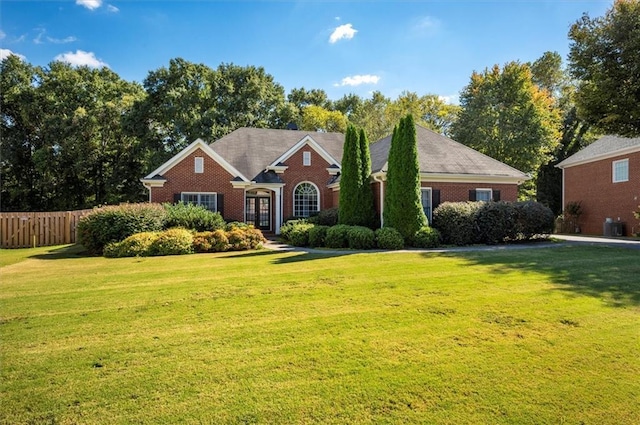 view of front of house featuring brick siding, a front yard, and fence